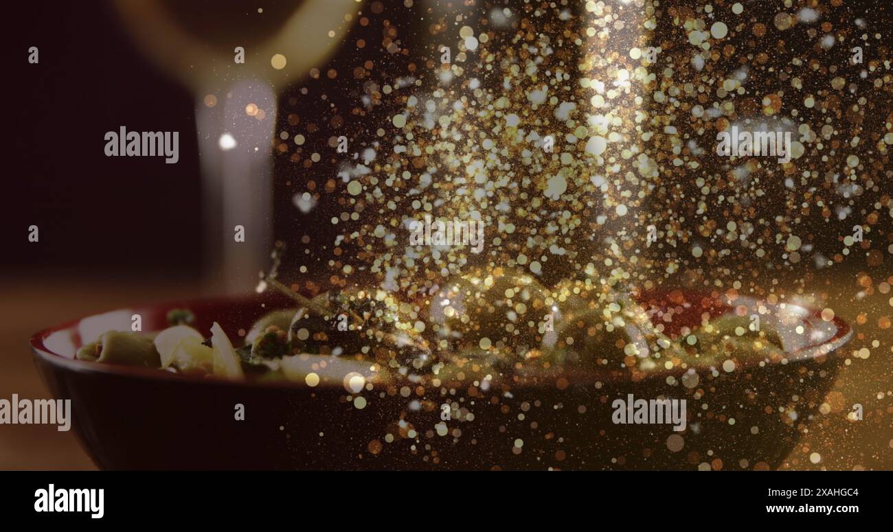 Immagine di punti d'oro su un bicchiere sfocato di vino bianco e piatto con olive Foto Stock