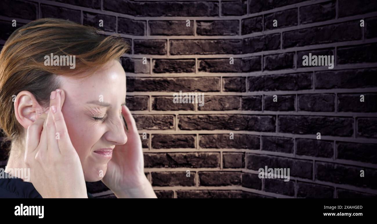 Vista ravvicinata di una donna caucasica stressata che tiene la testa contro un muro di mattoni sullo sfondo Foto Stock
