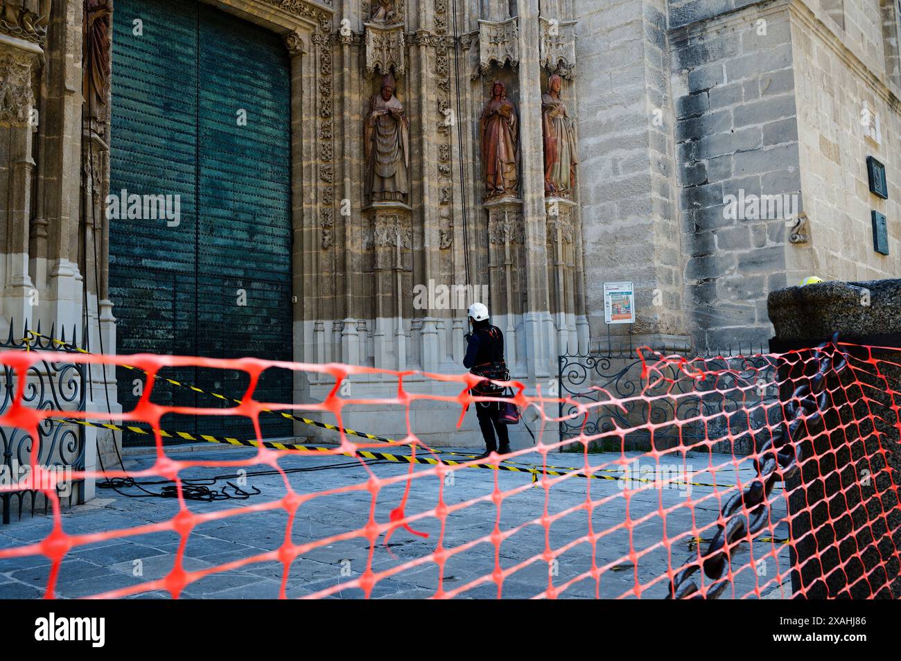 Operaio dotato di attrezzatura da arrampicata, pronto a eseguire la manutenzione sulla facciata ornata della storica cattedrale di Siviglia Foto Stock