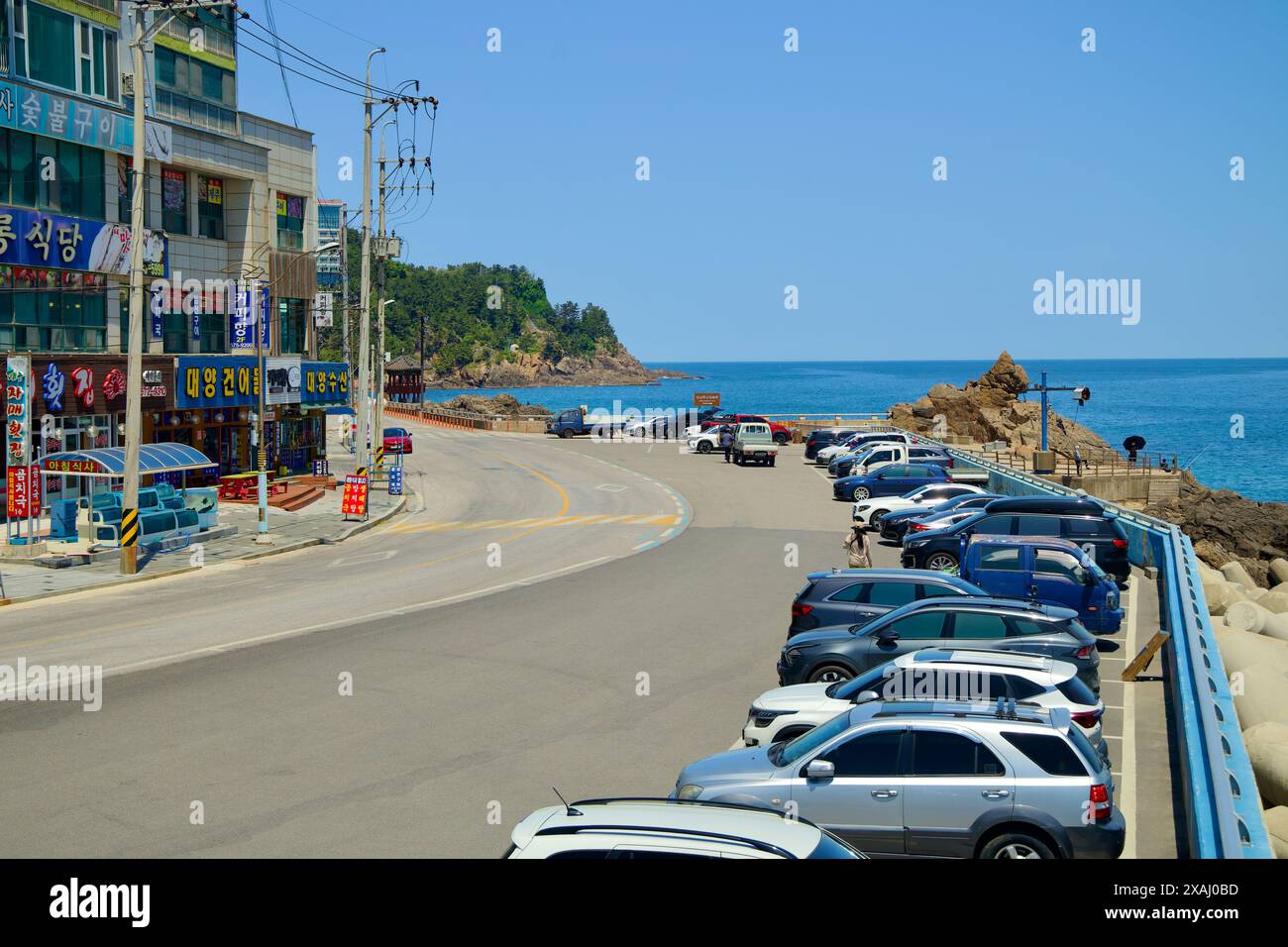 Samcheok City, Corea del Sud - 18 maggio 2024: Una vista verso Lion Rock da Isabu Plaza, che mostra la strada costiera costeggiata da auto parcheggiate e locali Foto Stock