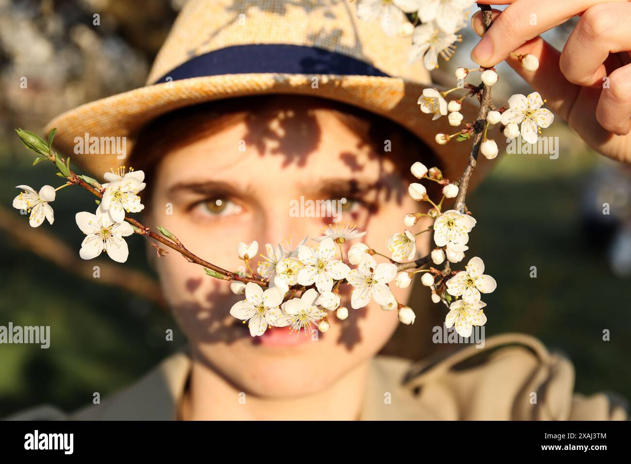 Donna con occhi verdi, fiori di ciliegio in primavera, arte ispirata alla natura. Cattura artistica di una donna. Bellezza primaverile, donna tra i fiori di ciliegio, ar Foto Stock