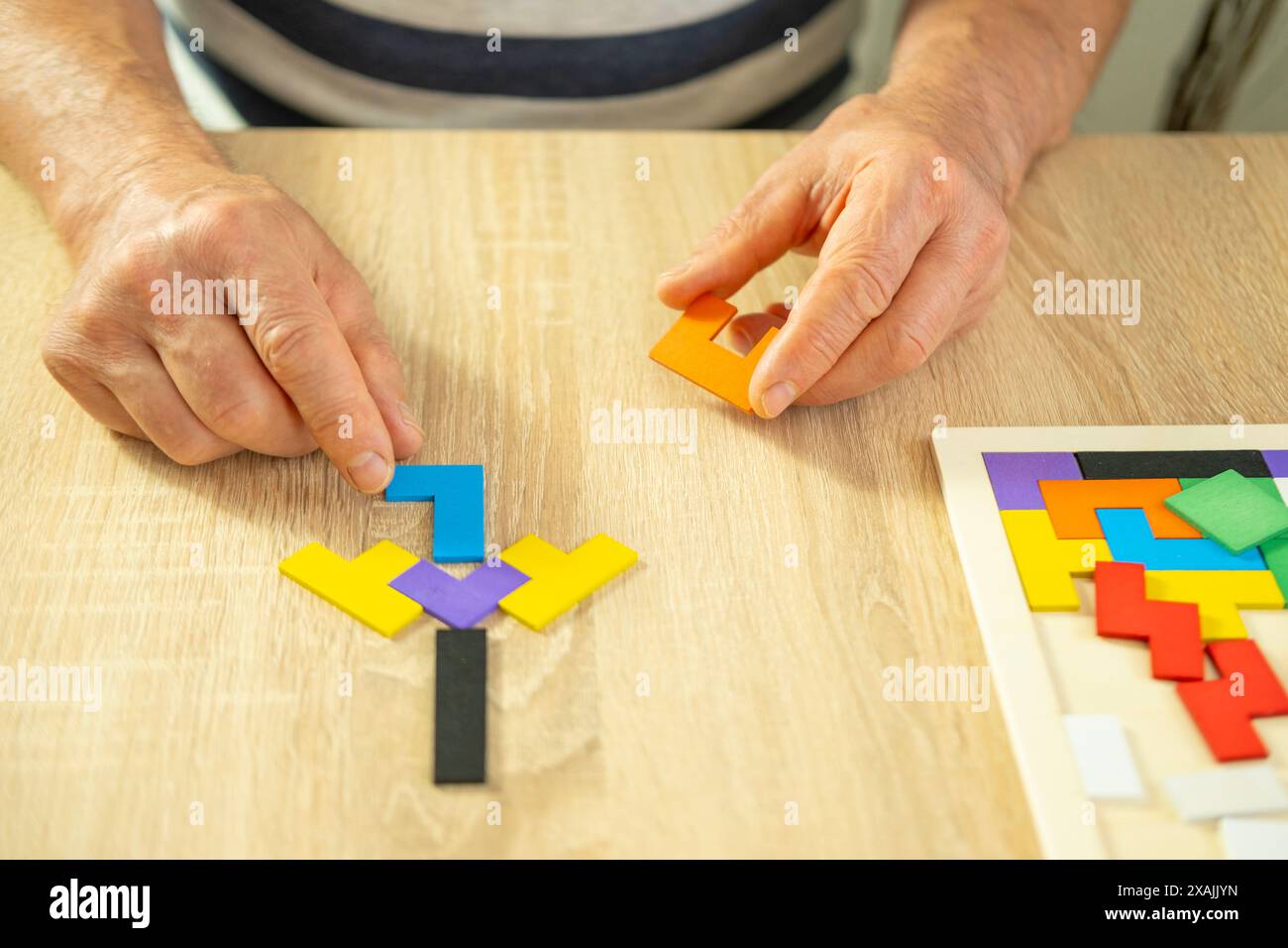mano maschile manipola puzzle di legno colorato, vecchio anziano che compone forme geometriche, salute del cervello e benessere mentale, prevenire la demenza e. Foto Stock