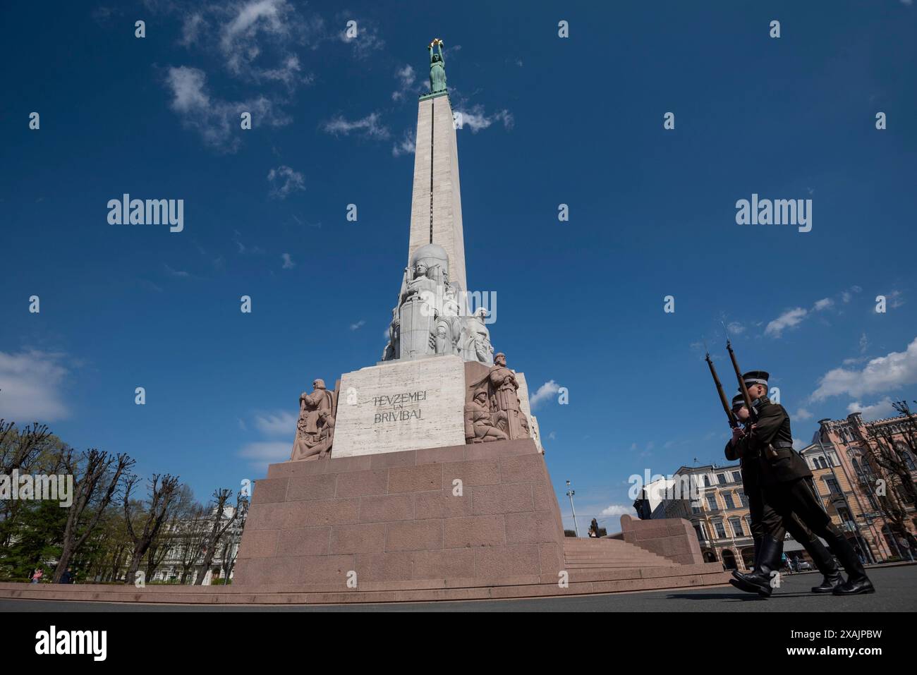 Due soldati marciano di fronte al Monumento alla libertà di riga. Il monumento è stato dedicato nel 1935 e reca l'iscrizione "per la patria e la libertà", riga, Lettonia Foto Stock