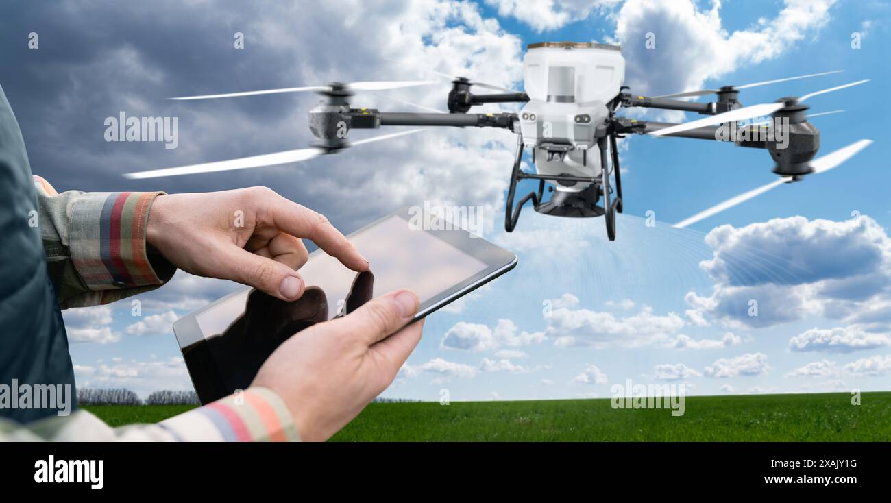 Agricoltore con tablet controlla lo spargimento di droni agricoli che diffondono fertilizzante. Agricoltura intelligente e agricoltura di precisione. Foto Stock