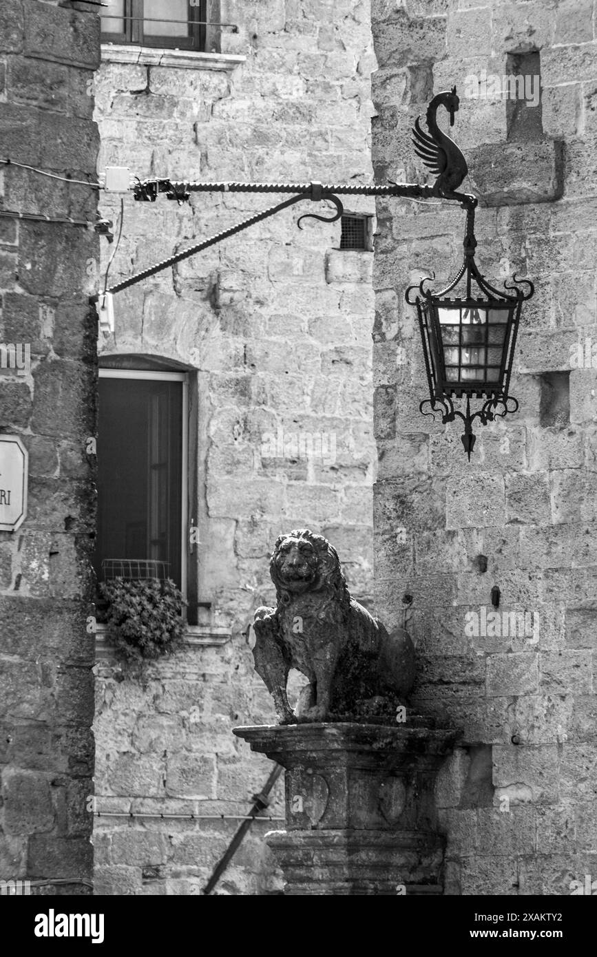 Una statua di leone e un antico lampione d'epoca nella città di Volterra, Italia Foto Stock