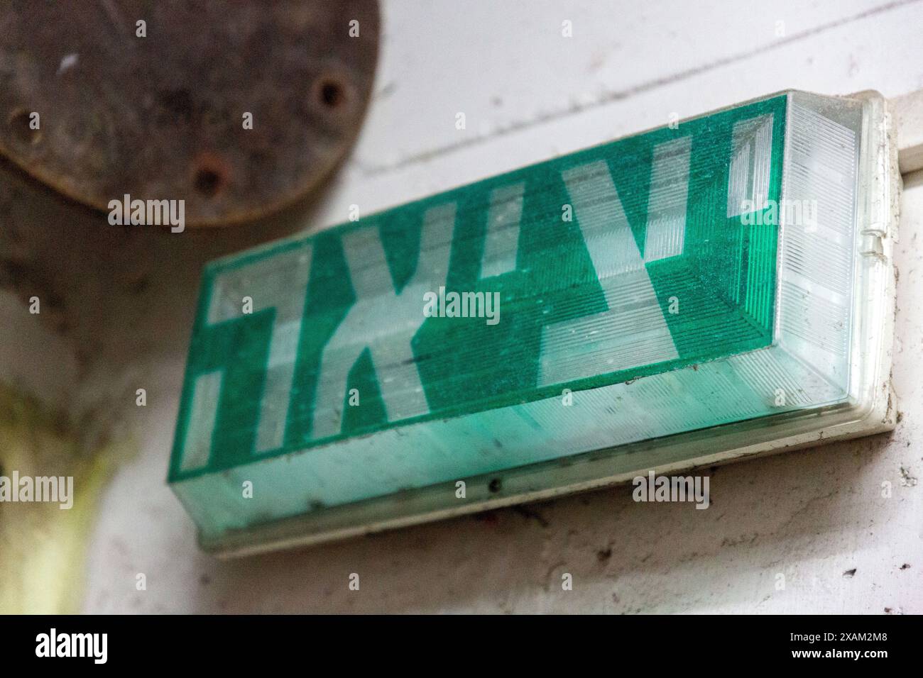Cartello di uscita in ebraico, segnaletica verde che indica la strada per uscire in un seminterrato di cemento invecchiato Foto Stock