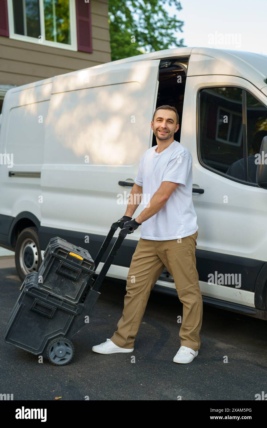 Sorridendo caucasico Contractor Worker nei suoi 40s caricando le sue scatole di attrezzi al suo furgone commerciale. Tema veicoli commerciali. Foto Stock