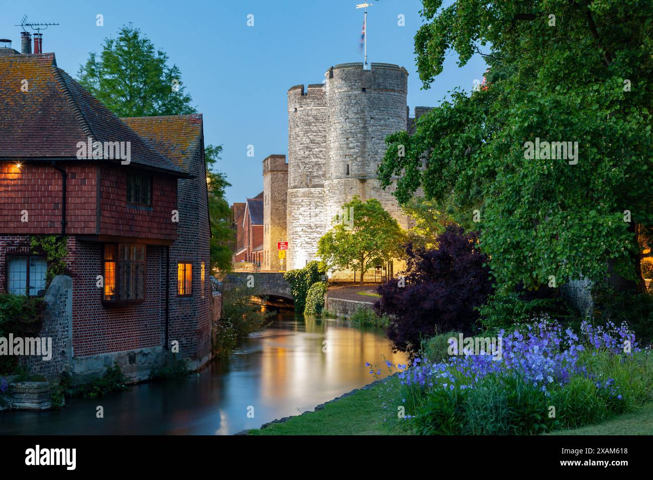 La notte cade ai Westgate Gardens di Canterbury, Inghilterra. Westgate Towers illuminate in lontananza. Foto Stock