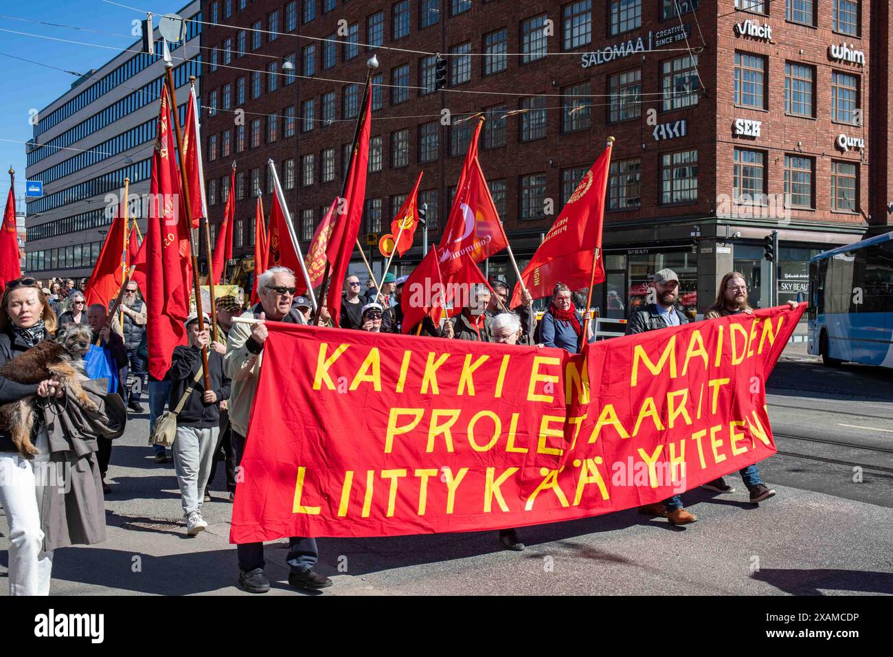 Kaikkien, proletaarit liittykää yhteen. Comunisti che portano una grande bandiera rossa durante la marcia del Labor Day nel quartiere Hakaniemi di Helsinki, Finlandia. Foto Stock