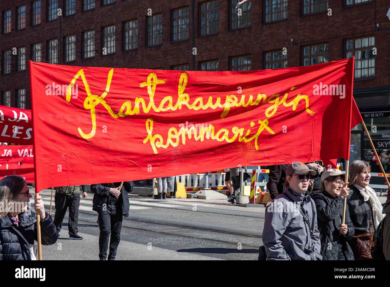 Kantakaupungin kommarit. Comunisti che portano striscione rosso alla marcia del Labor Day su Siltasaarenkatu nel distretto di Hakaniemi di Helsinki, Finlandia. Foto Stock