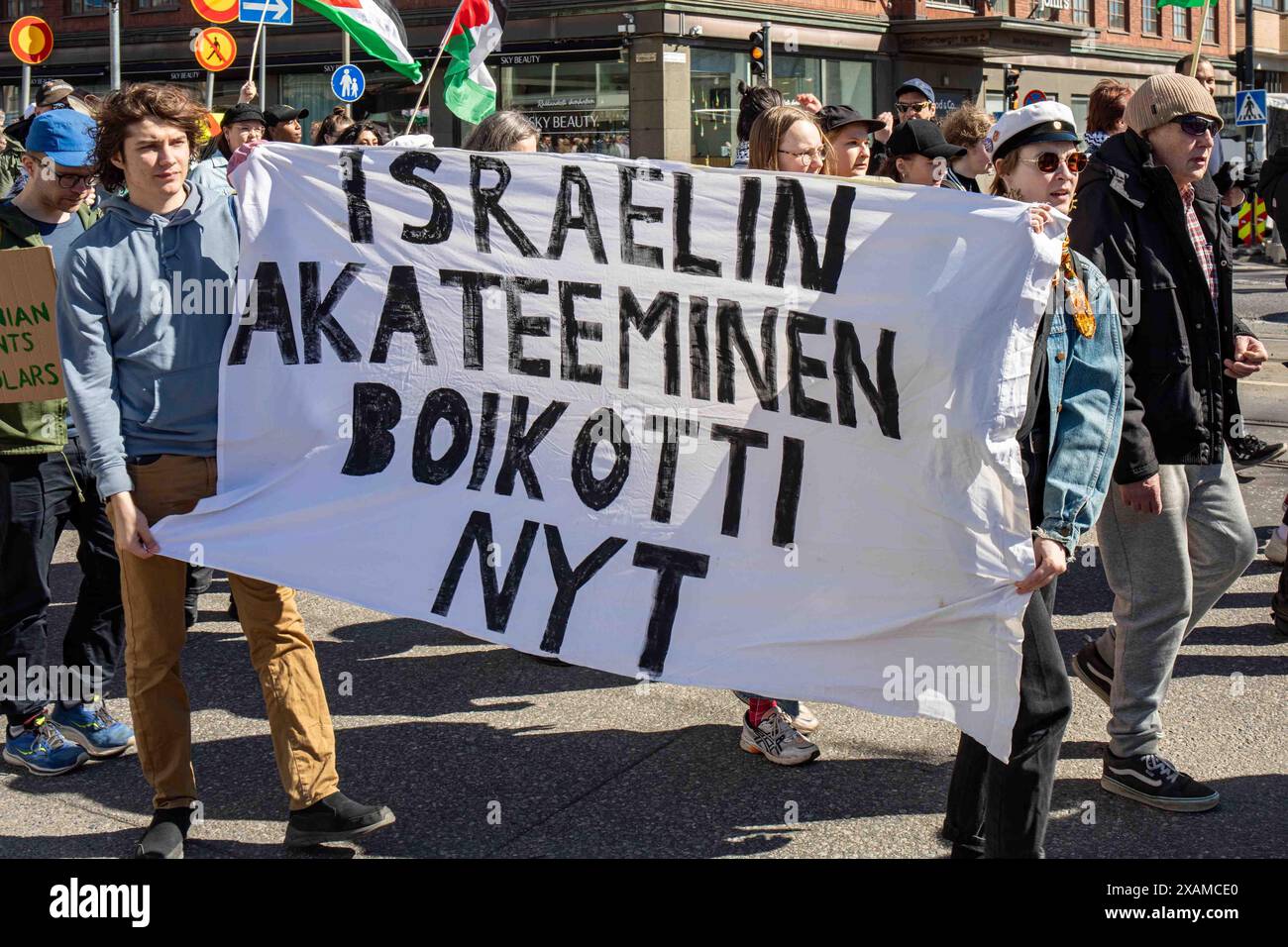 Israelin akateeminen boikotti nyt. Dimostranti che portano un grande striscione alla marcia del Labor Day nel quartiere Hakaniemi di Helsinki, Finlandia. Foto Stock