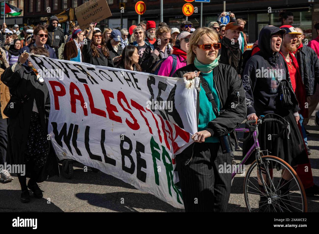 River to the Sea Palestine sarà libera. Manifestanti che portano un grande striscione alla marcia del Labor Day nel quartiere Hakaniemi di Helsinki, in Finlandia. Foto Stock