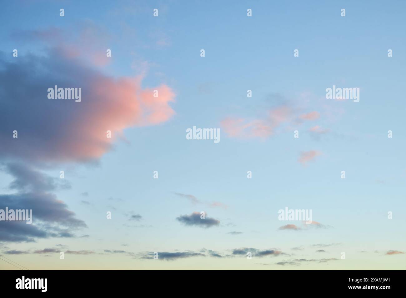 Un frammento di un cielo luminoso al tramonto con nuvole dalla forma bizzarra. Accattivante cielo crepuscolo con una gamma di tonalità calde, perfetto per il tuo progetto di design Foto Stock