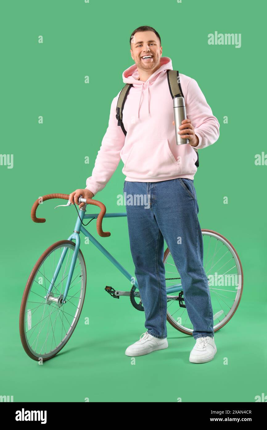 Turista maschile con zaino e bicicletta su sfondo verde Foto Stock