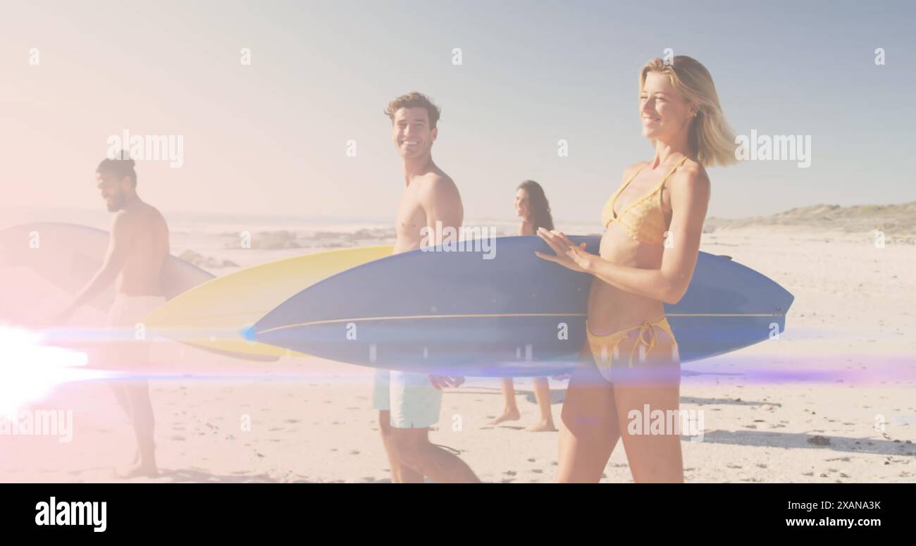Immagine di luce su amici felici e diversi che camminano sulla spiaggia con tavole da surf Foto Stock