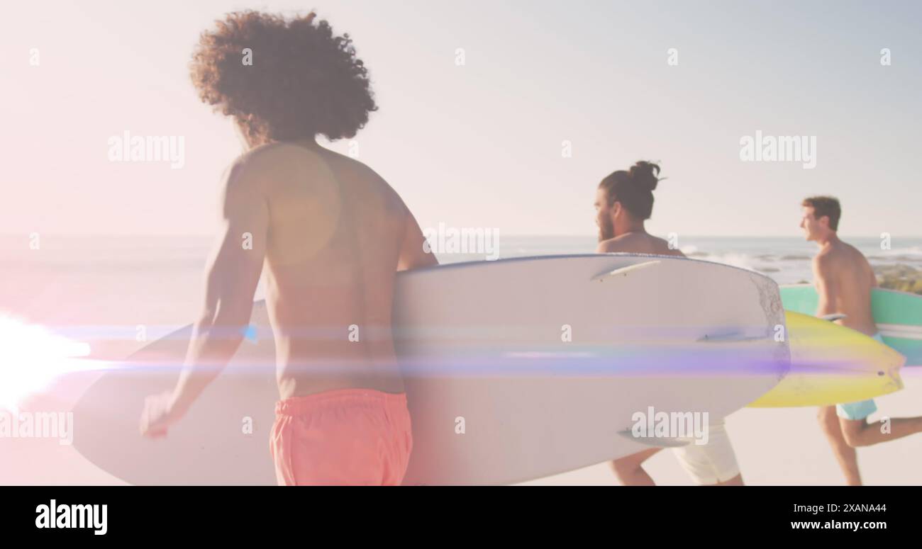 Immagine di luce su amici maschi felici e diversi che corrono sulla spiaggia con tavole da surf Foto Stock