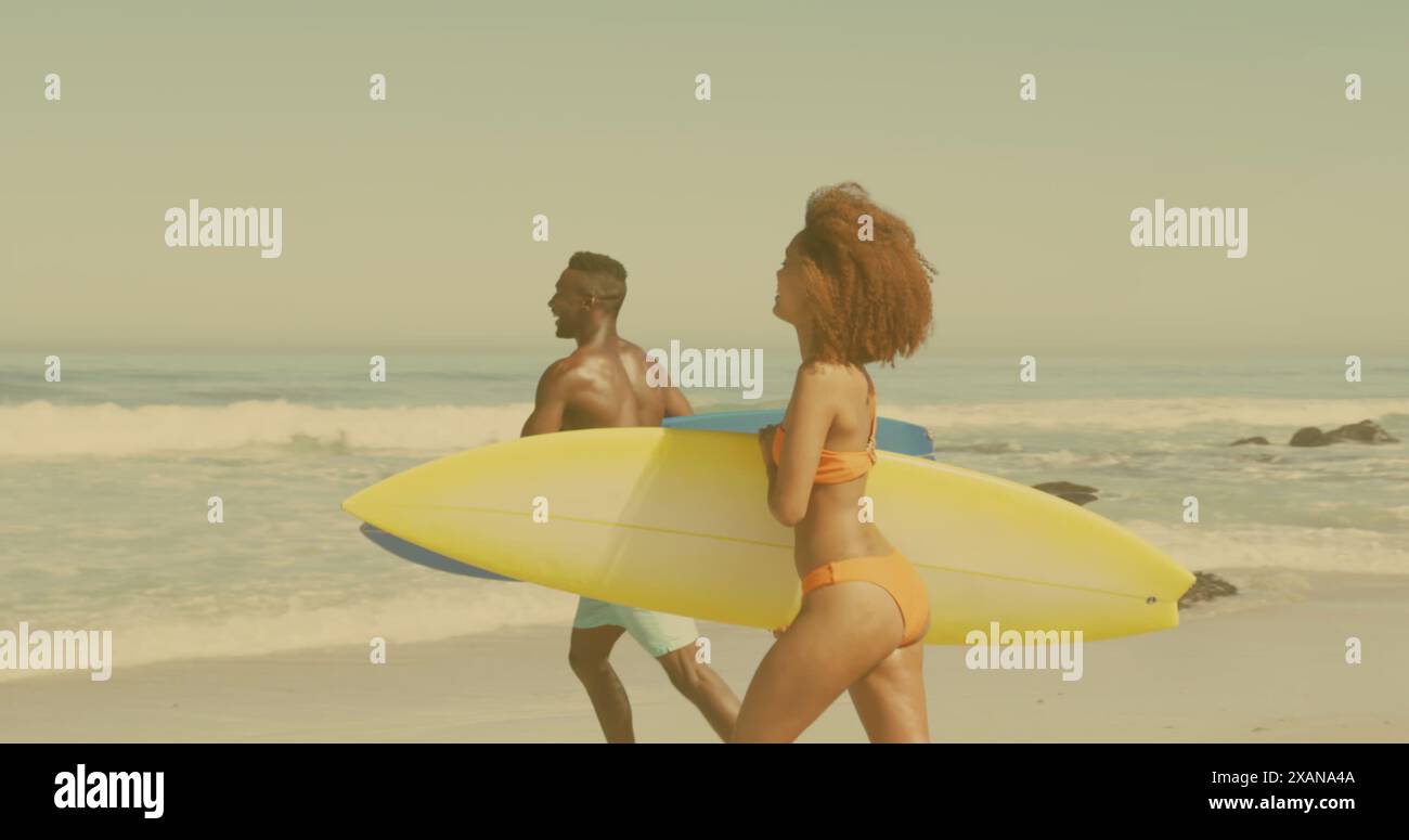 Immagine della luce sulla coppia afroamericana che cammina con tavole da surf sulla spiaggia Foto Stock