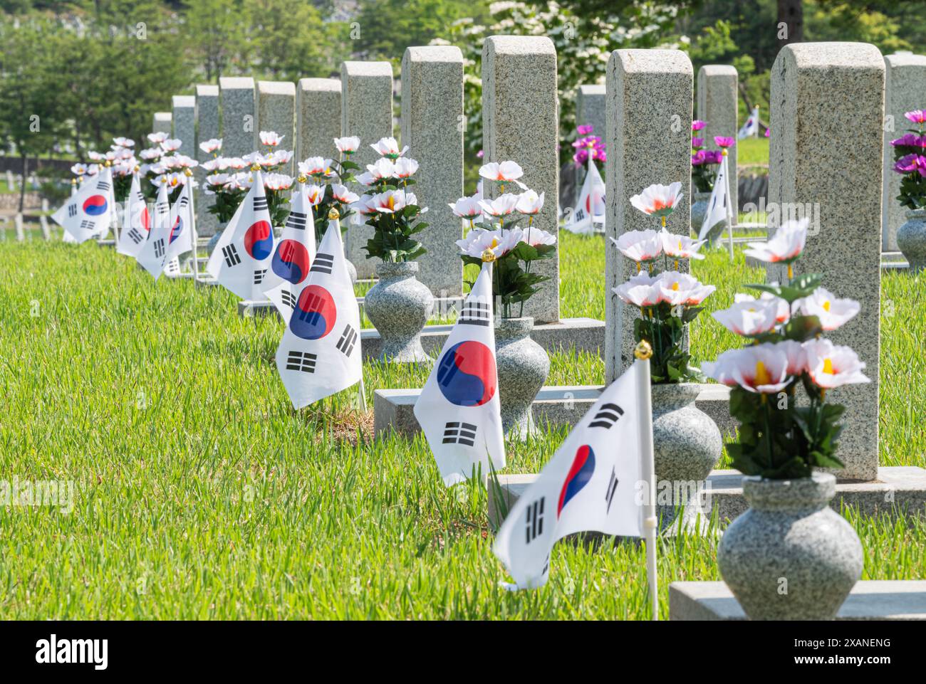 Un paesaggio con una lapide e una bandiera coreana su un prato verde Foto Stock