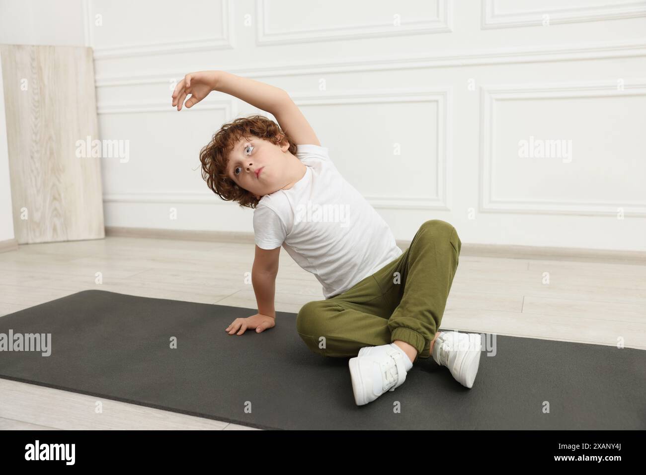 Ragazzo che fa esercizi ginnici sul tappeto in casa Foto Stock Ragazzo che fa esercizi ginnici sul tappeto in casa Foto Stock