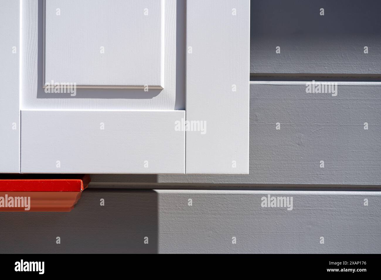 Persiane bianche su una facciata grigia con rosso Foto Stock