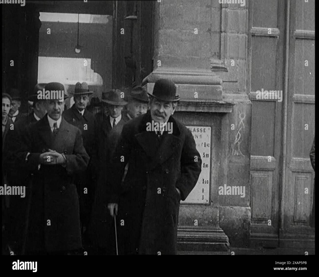 Il primo ministro francese Aristide Briand in piedi fuori con un gruppo di civili maschi in Hats, 1926. "Anche se la Germania sembrava instabile, le altre nazioni occidentali ritenevano opportuno ammetterla nella società delle Nazioni. "Beh, meglio dentro che fuori", hanno detto molti. Gli oppositori tradizionali della Germania come la Francia, mantenevano i loro veri pensieri per se stessi, ma la lasciavano entrare. Da "Time to Remember 1926 - Short Sharp Shower"- Reel 1; un documentario sul 1926 - General Strike, politica internazionale, danza, meteo e imprese da record. Foto Stock