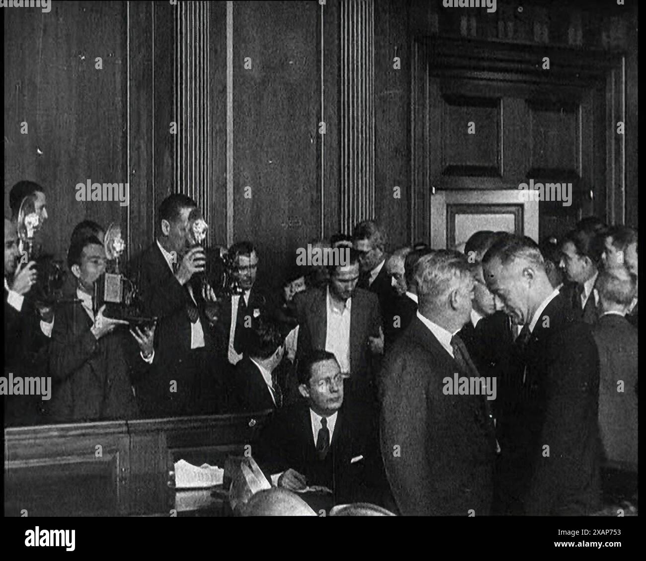 Bruno Richard Hauptmann che entra in una sala di tribunale per un'udienza Bail in relazione al caso di Lindbergh, i membri della stampa sono visti scattare foto, anni '1930 Hauptmann: "Un uomo i cui registri precisi dei suoi risparmi e delle sue spese mostravano che mentre era in America aveva speso 49.950 dollari in più di quanto avesse guadagnato". Da Time to Remember - The Tough Guys, 1930s (Reel 3); film documentario, principalmente sulla vita in depressione e gangster-hit America. Foto Stock