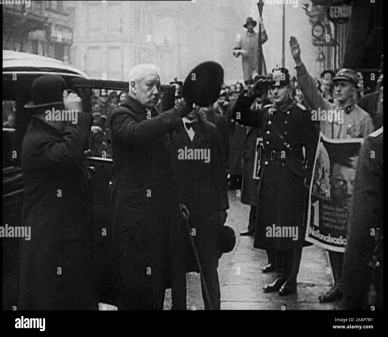 Il presidente tedesco Paul von Hindenburg saluta una folla, 1933. "Sebbene sospettoso fosse del Partito [Nazionalsocialista], l'anziano presidente Hindenburg ha scelto di sostenerlo come il meno di molti mali”. Nota poster di Hindenburg e del suo cancelliere Adolf Hitler a destra. Da "Time to Remember - The Time of the Monster", 1933 (Reel 2); film documentario sugli eventi del 1933, Rise of Roosevelt e Hitler. Foto Stock