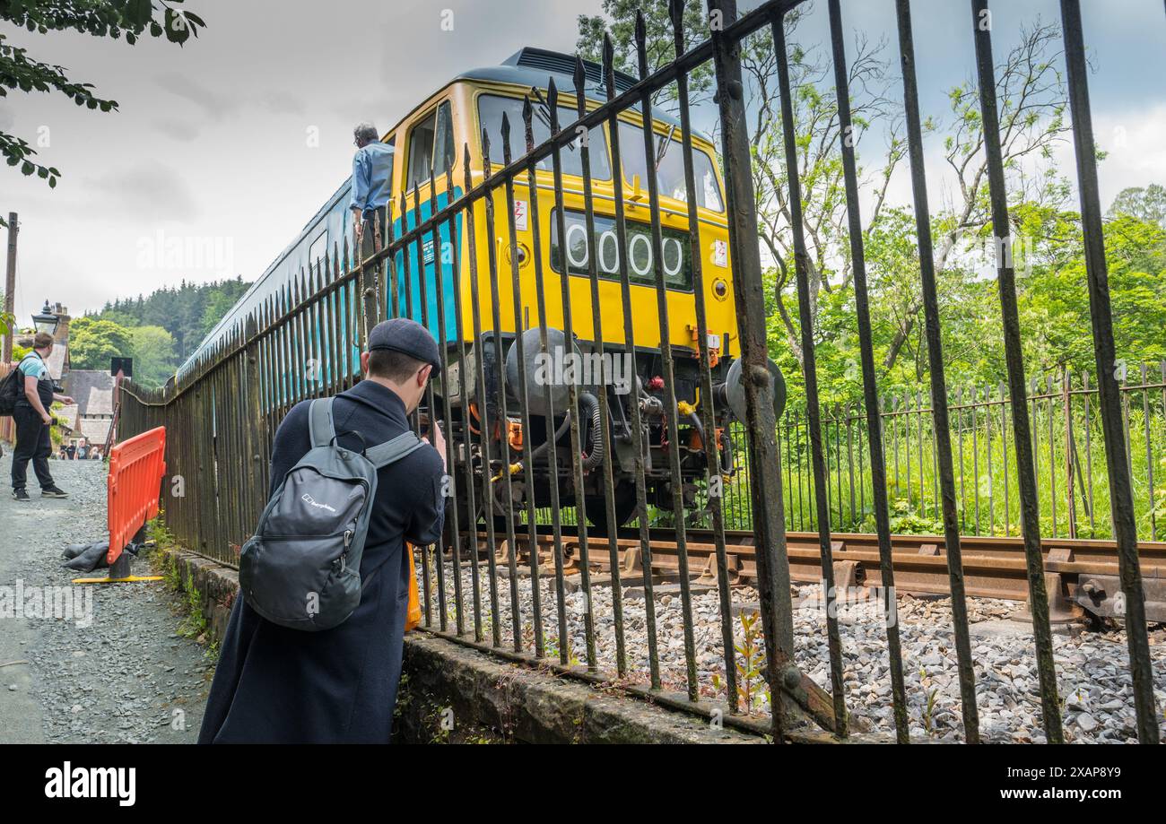 Osservatore di treni ferroviari che fotografa un treno diesel classe 47 che opera sulla ferrovia Llangollen alla stazione ferroviaria di Berwyn nel Galles del Nord. Foto Stock