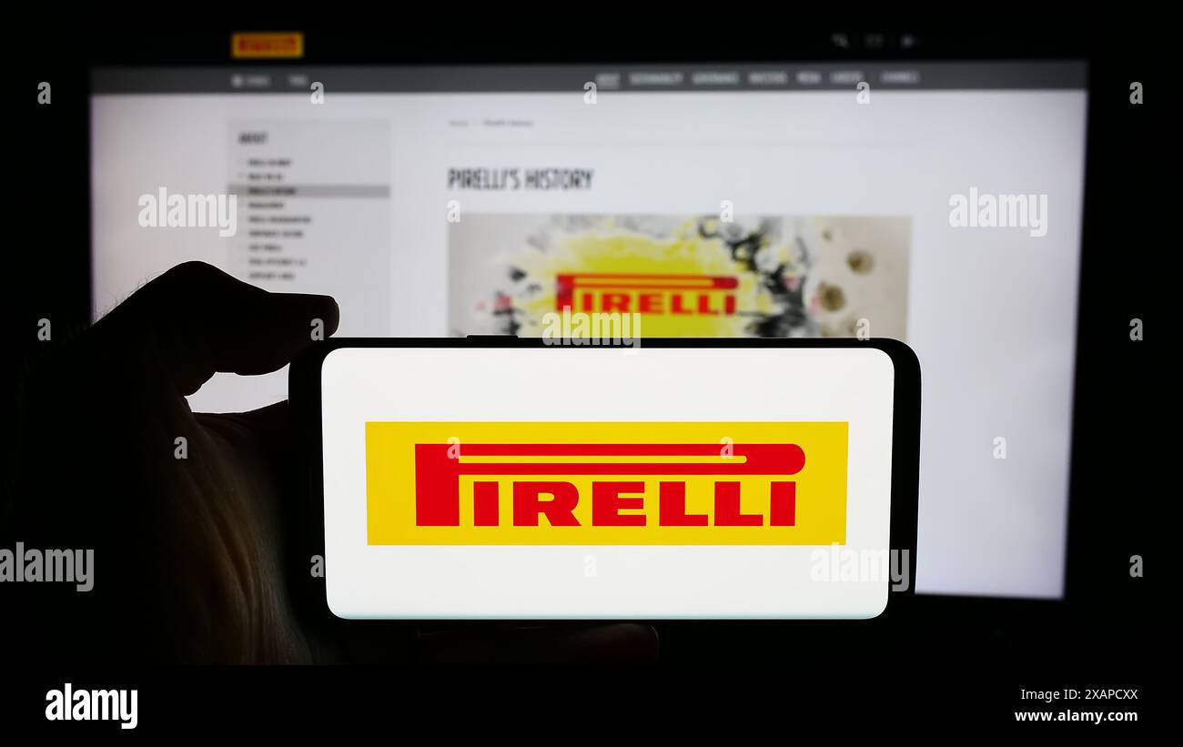 Persona che detiene il cellulare con il logo dell'azienda italiana di produzione pneumatici Pirelli C. S.p.A. davanti alla pagina web aziendale. Mettere a fuoco il display del telefono. Foto Stock