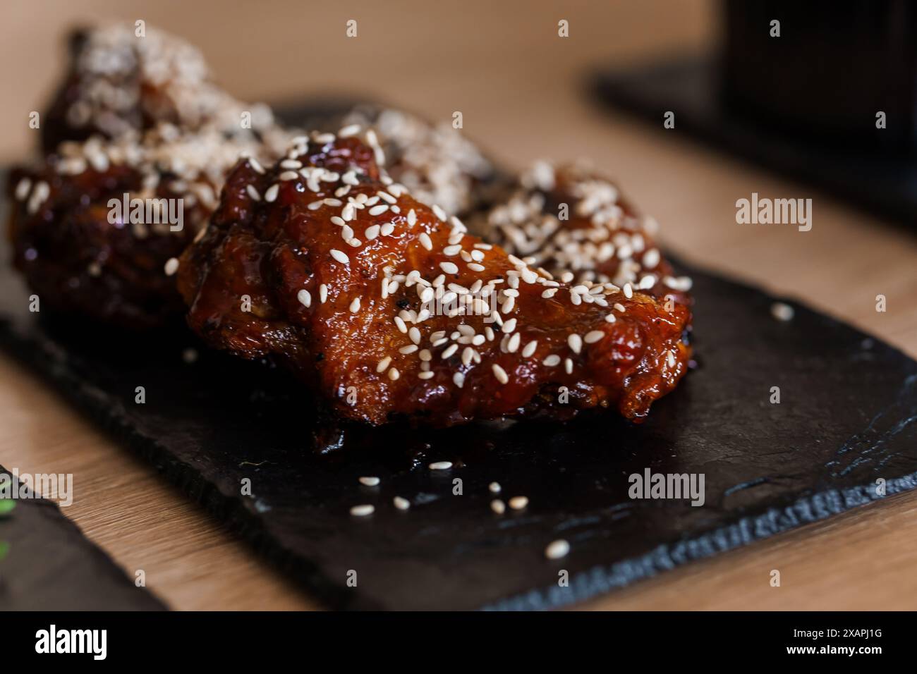Ali di pollo in salsa al miele di soia con semi di sesamo su un bordo nero Foto Stock