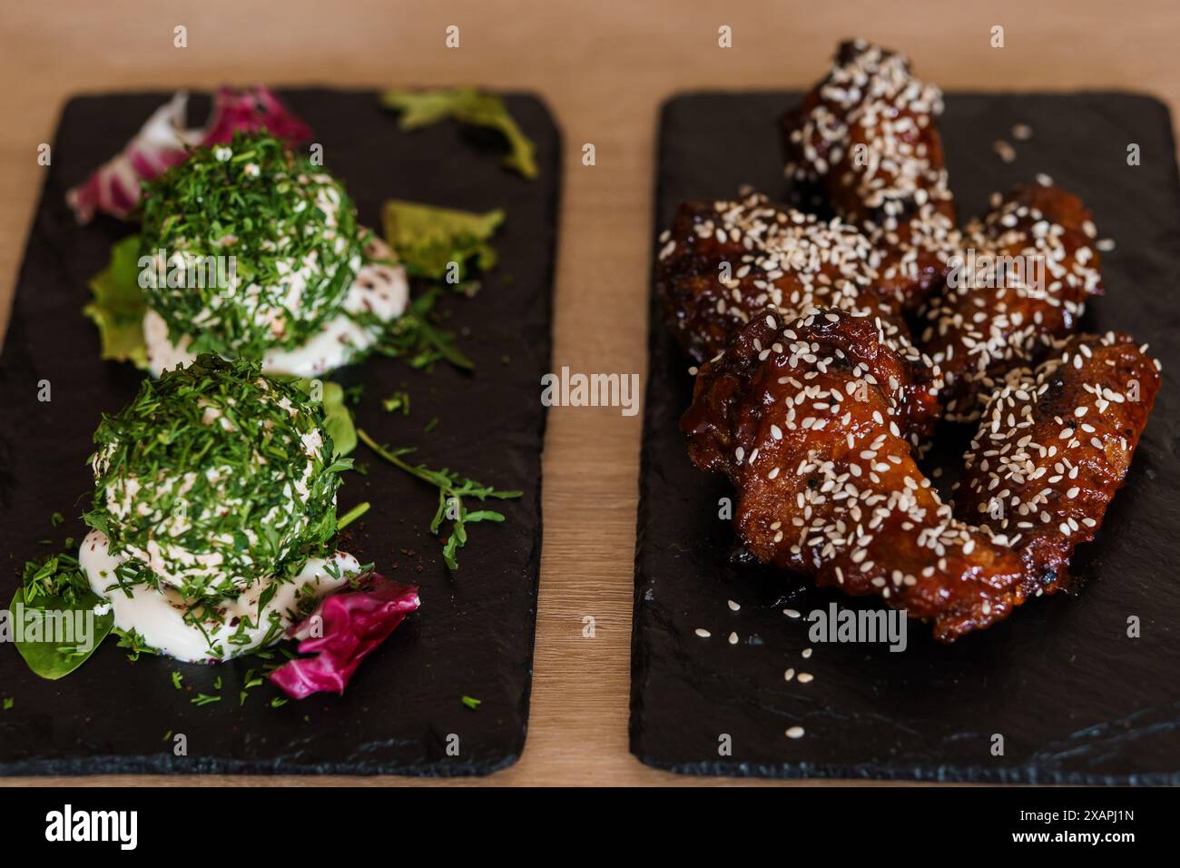 Ali di pollo in salsa al miele di soia con semi di sesamo su un bordo nero Foto Stock
