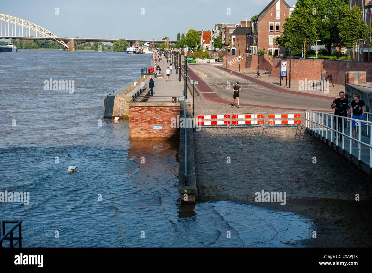 Si vedono persone passare davanti a un'area allagata. Le persistenti piogge nella Germania meridionale stanno causando un aumento del livello dell'acqua nella zona olandese vicino alla Germania. d. nella città di Lobith, al confine con la Gheldria, è stato misurato un livello di 12,85 metri sopra il piano nazionale di pesca (la base utilizzata per misurare il livello dell'acqua). A Nijmegen, parti basse della banchina e intorno al porto di Waalkade sono sott'acqua. Il livello dell'acqua del Reno ha raggiunto un picco il venerdì mattina, ma era meno alto di quanto inizialmente previsto. L'aspettativa era che l'acqua salisse a più di 13 metri sopra NAP. (Foto di Ana Ferna Foto Stock