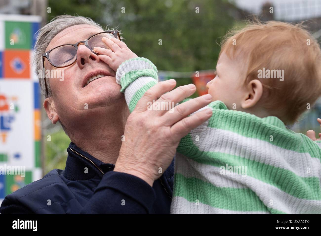 Il leader del Partito laburista Sir Keir Starmer tiene un bambino piccolo durante la sua visita all'Harlesden Town Garden nel nord-ovest di Londra, mentre si trova sulle tracce della campagna elettorale generale. Data foto: Sabato 8 giugno 2024. Foto Stock