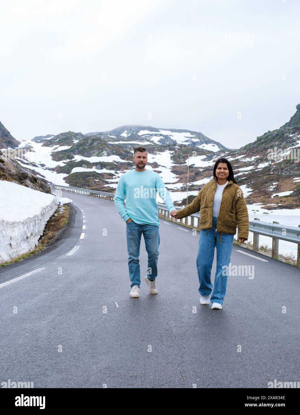 Un paio di uomini e donne su una strada innevata, una coppia variegata sulla Lyse Road coperta di neve fino a Krejag Norvegia Lysebotn Foto Stock