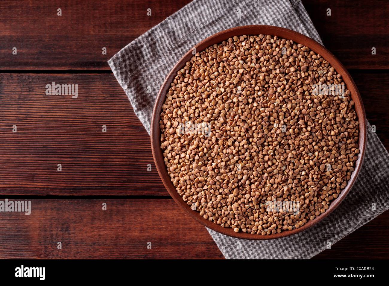 Grano saraceno integrale su tavolo da cucina rustico con tovagliolo in lino, spazio per copie Foto Stock