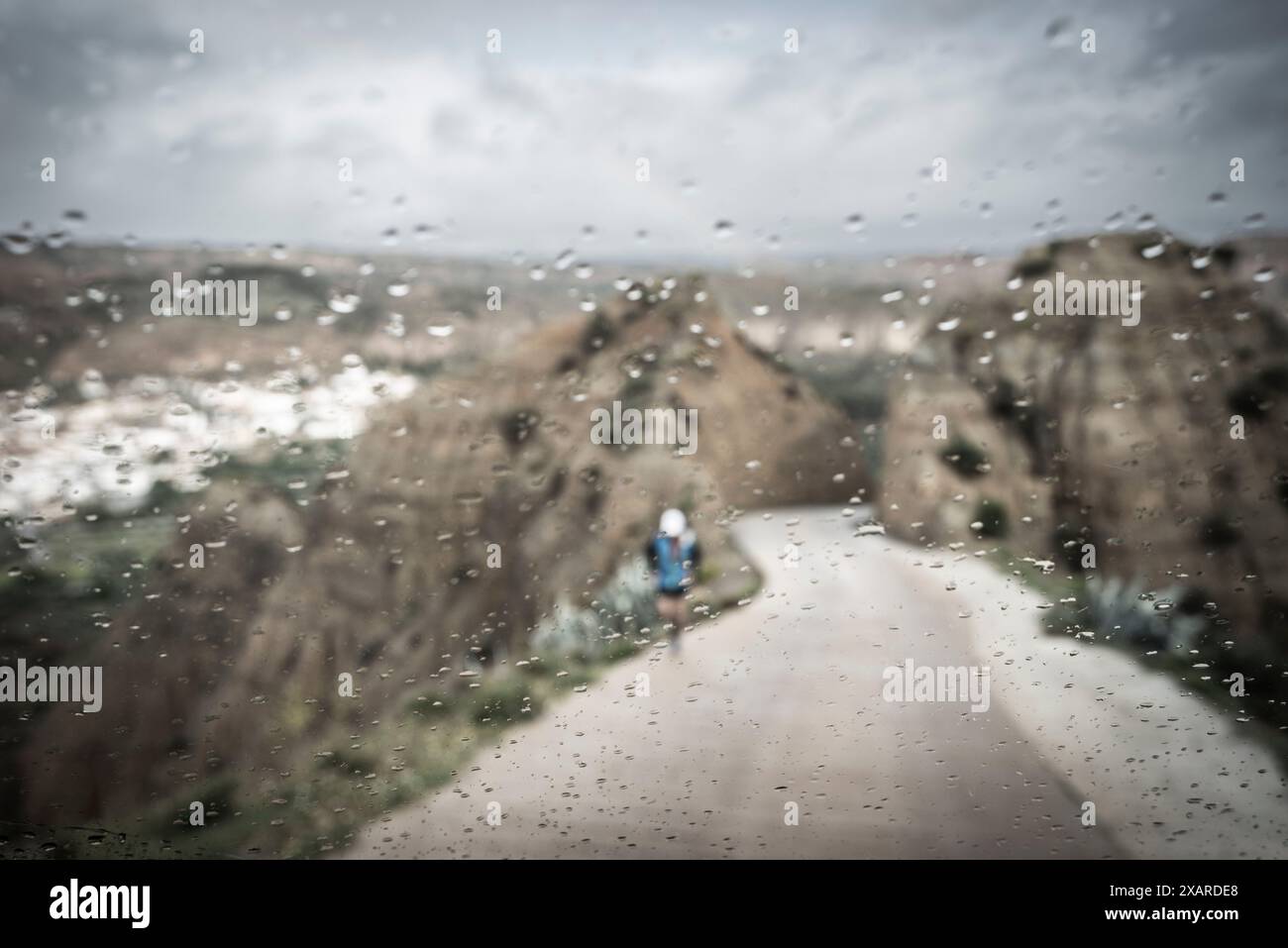 Corridore solitario sotto la pioggia, ascesa al punto panoramico di fin del Mundo, Beas de Guadix, Granada Geopark, provincia di Granada, Andalusia, Spagna. Foto Stock