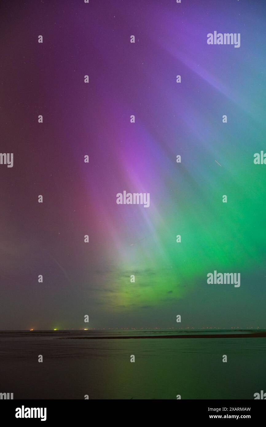 I colorati raggi di luce boreale sopra il mare sembrano provenire da un punto Foto Stock