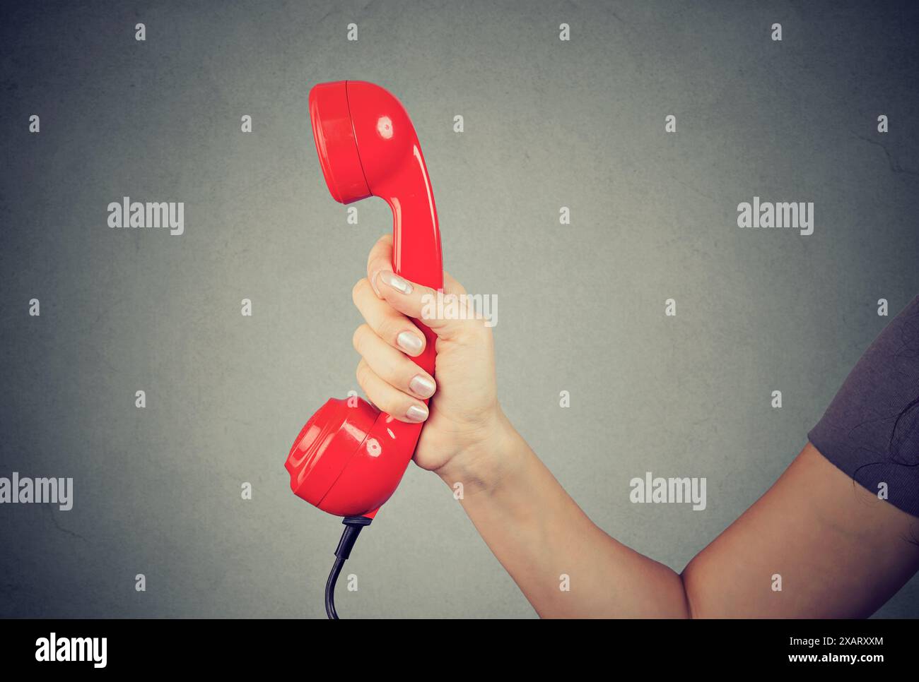 primo piano di un uomo che tiene la mano e mostra il ricevitore del telefono rosso. Foto Stock