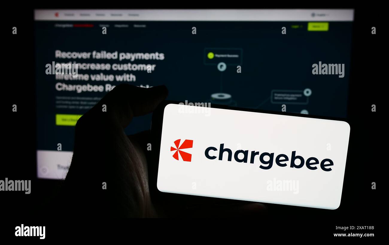 Persona che detiene un telefono cellulare con il logo della società americana Chargebee Inc. Di fronte alla pagina Web. Mettere a fuoco il display del telefono. Foto Stock