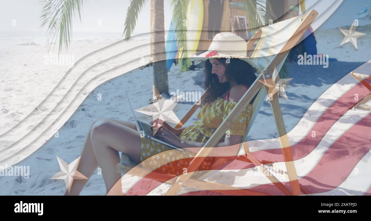 Più stelle su strisce blu contro una donna che utilizza un computer portatile seduto sulla sdraio in spiaggia Foto Stock