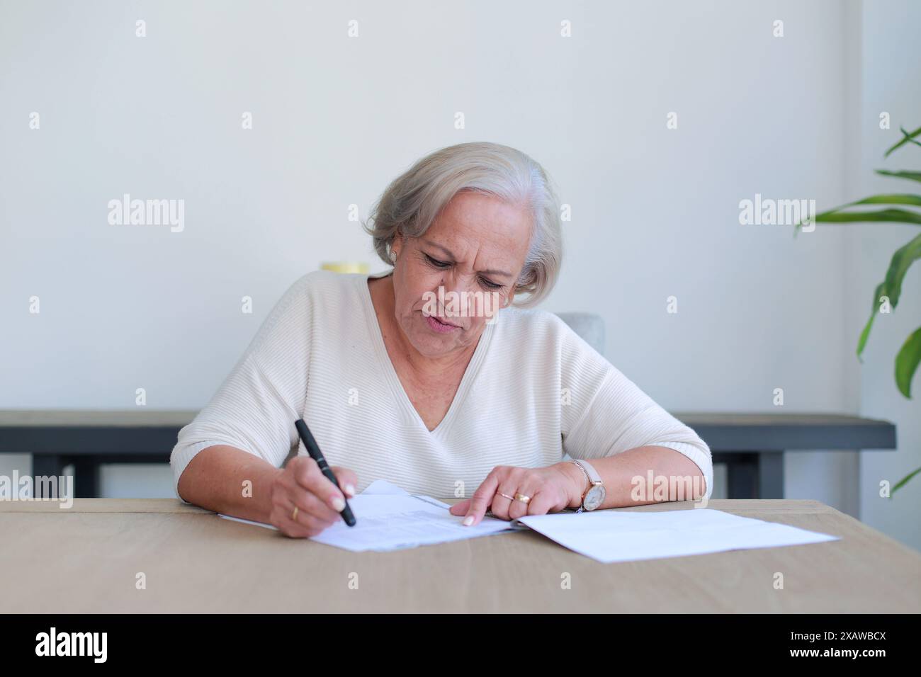 La signora premurosa esamina documenti importanti a casa Foto Stock
