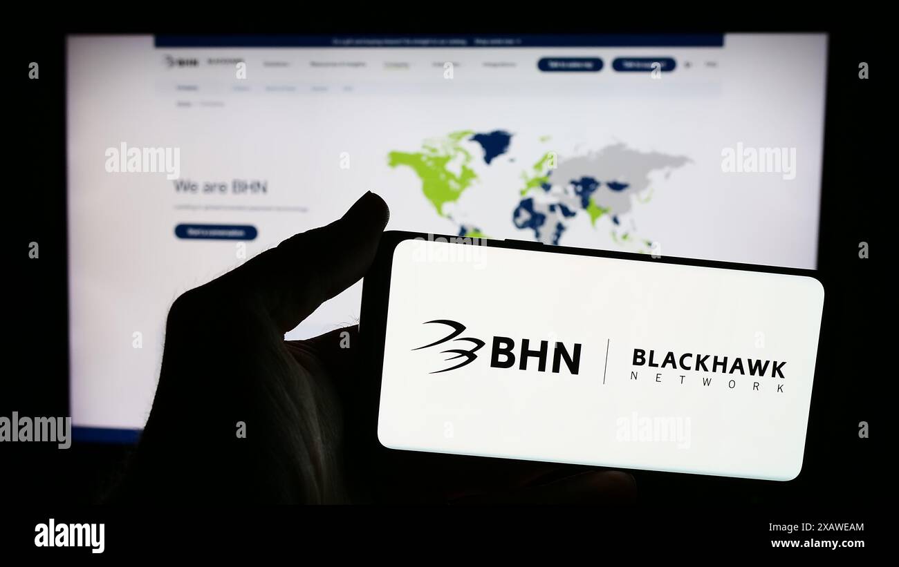 Persona che detiene lo smartphone con il logo della società di soluzioni di pagamento Blackhawk Network Holdings Inc. Davanti al sito Web. Mettere a fuoco il display del telefono. Foto Stock