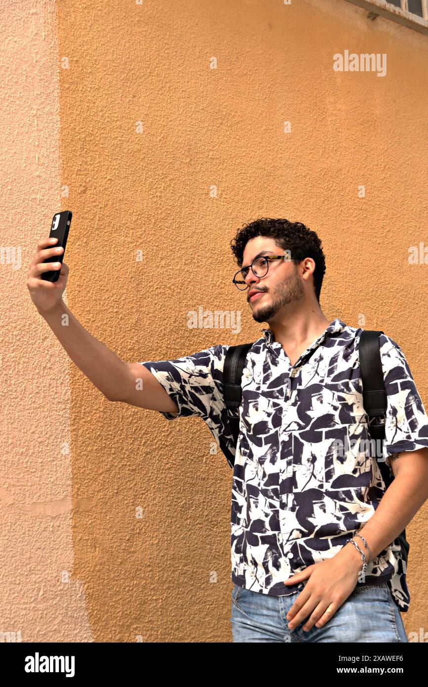 Stile di vita attivo: Un giovane moderno che realizza selfie con il suo cellulare un giovane moderno e attivo fa selfie con il suo cellulare. Stile di vita, tecnologia, auto-por Foto Stock