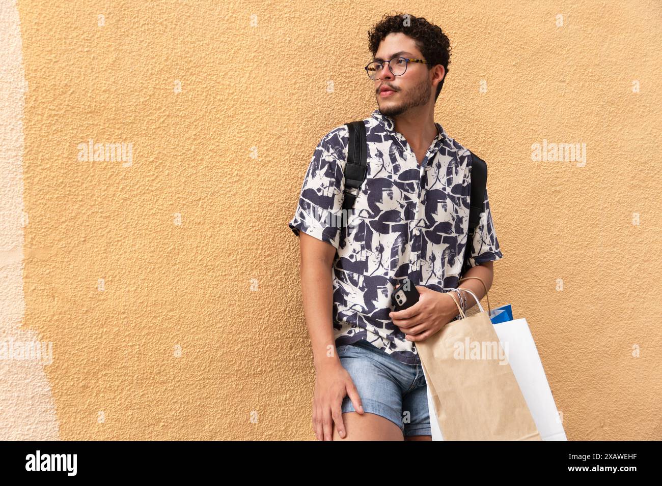 Urban Lifestyle: Giovane uomo con camicia stampata e borse per lo shopping. Moda urbana, stile di vita, città Foto Stock