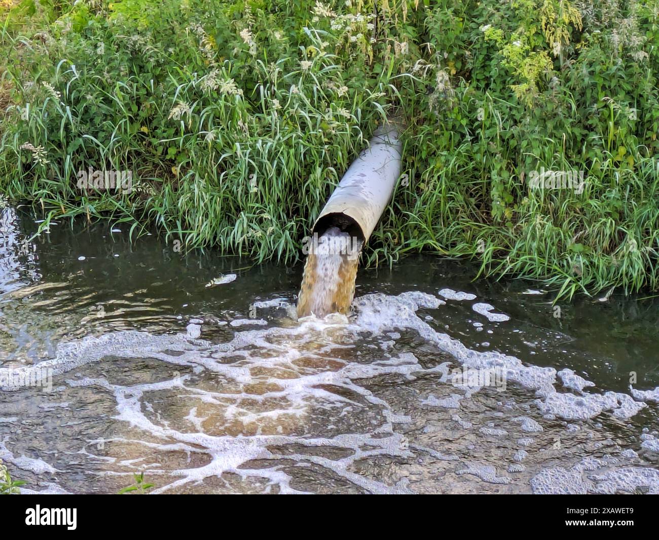 Tubo di deflusso dell'inquinamento nel fiume Foto Stock