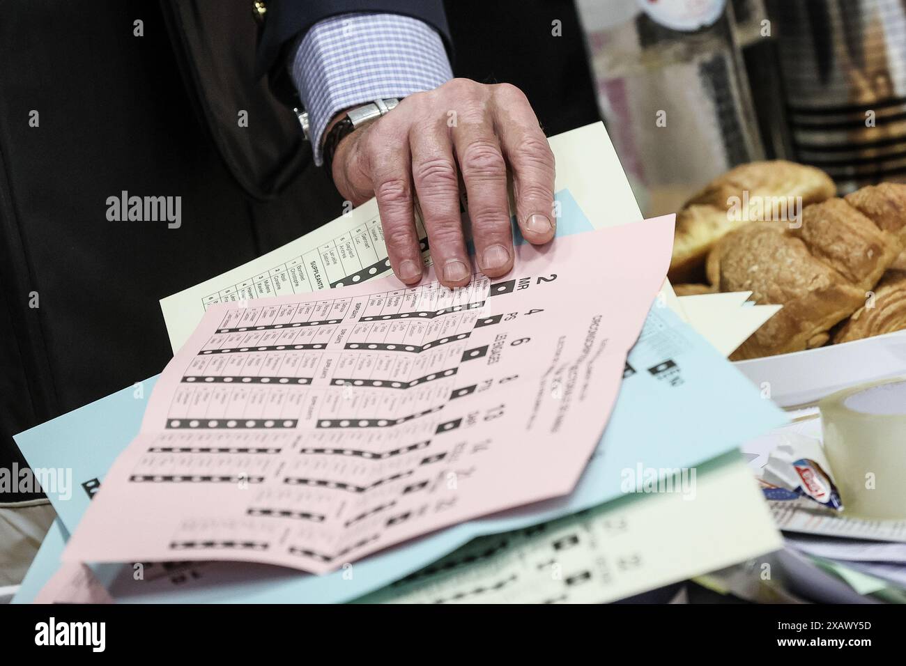 Una persona riceve le tre schede elettorali in una stazione elettorale di Namur, domenica 9 giugno 2024. Il Belgio tiene le elezioni per gli organi legislativi regionali, federali ed europei. FOTO DEL BELGA BRUNO FAHY Foto Stock