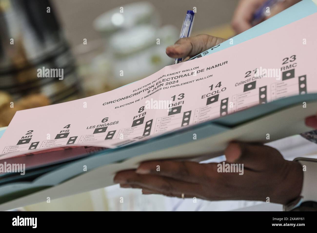 Una persona riceve le tre schede elettorali in una stazione elettorale di Namur, domenica 9 giugno 2024. Il Belgio tiene le elezioni per gli organi legislativi regionali, federali ed europei. FOTO DEL BELGA BRUNO FAHY Foto Stock