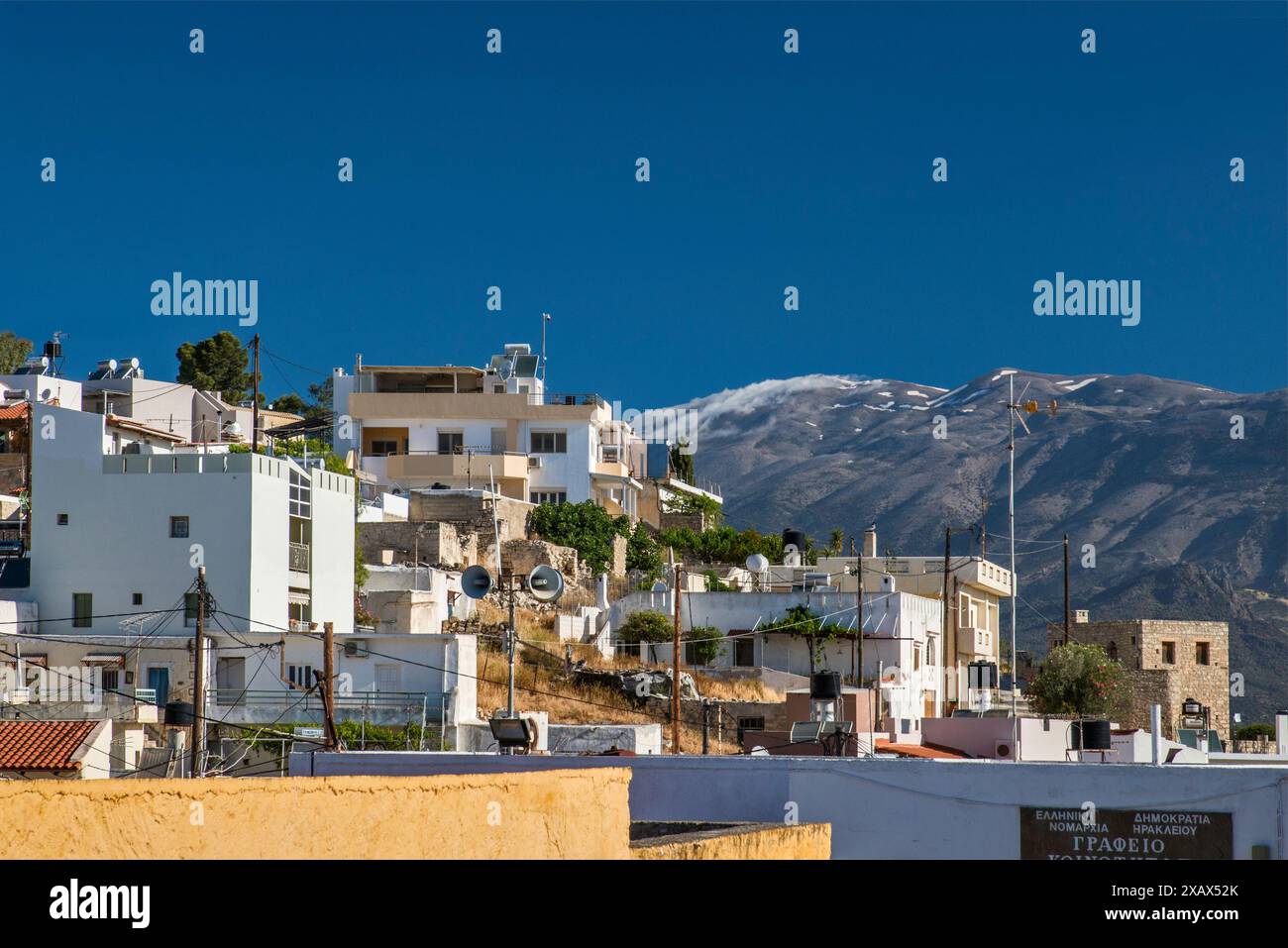 Case nel villaggio di Kamilari nella pianura di Mesara, cresta innevata del massiccio del Monte Psiclorite a dist, Psiloritis Geopark, inizio maggio, Creta, Grecia Foto Stock