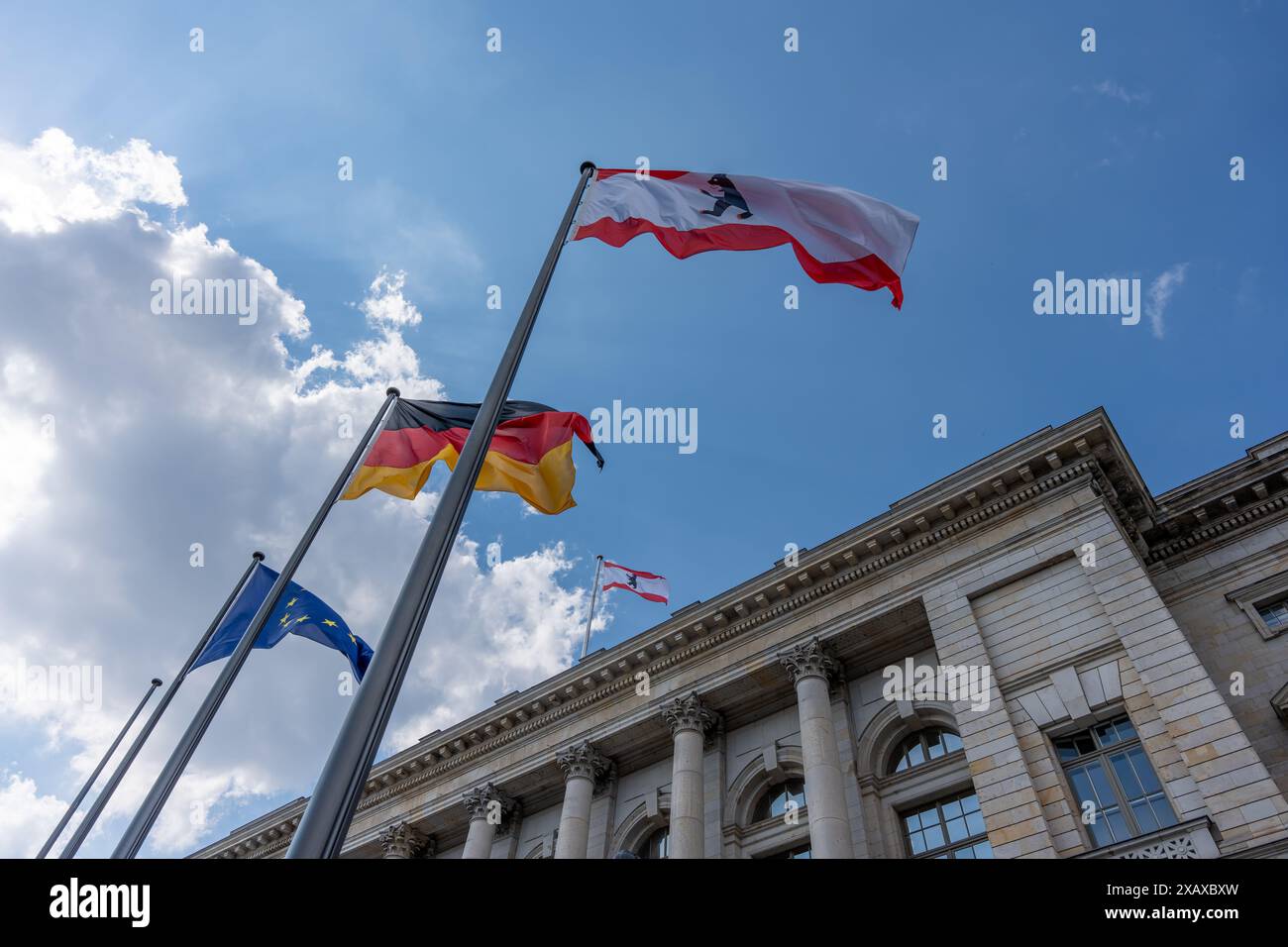 Un gruppo di bandiere sta volando nel cielo sopra un edificio. Le bandiere sono di colori e dimensioni diversi e sono disposte in modo da creare una se Foto Stock