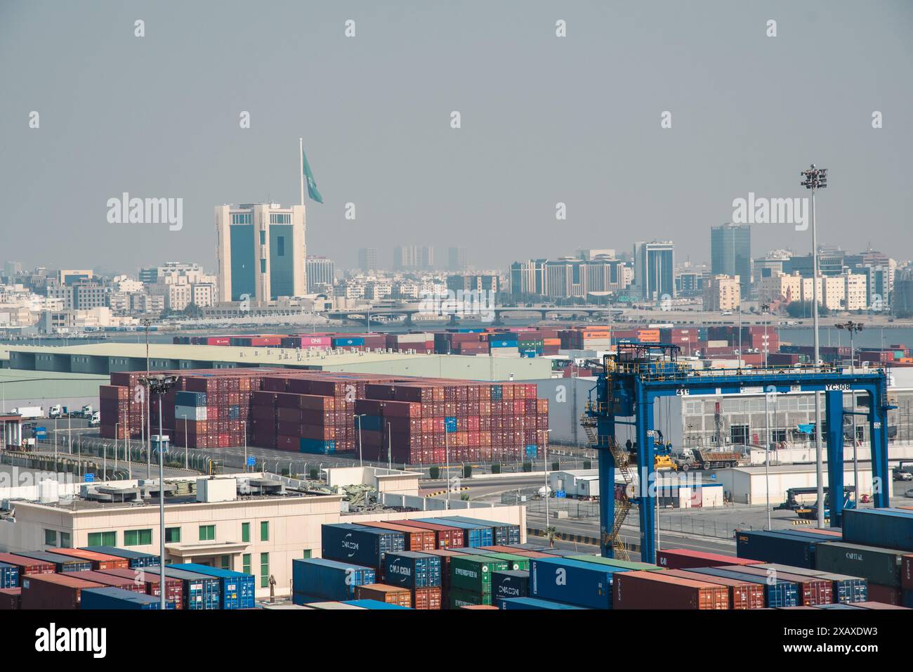 Jeddah, Arabia Saudita - 12 dicembre 2022: Una vivace scena portuale con container impilati che circondano lo skyline di Jeddah. Foto Stock